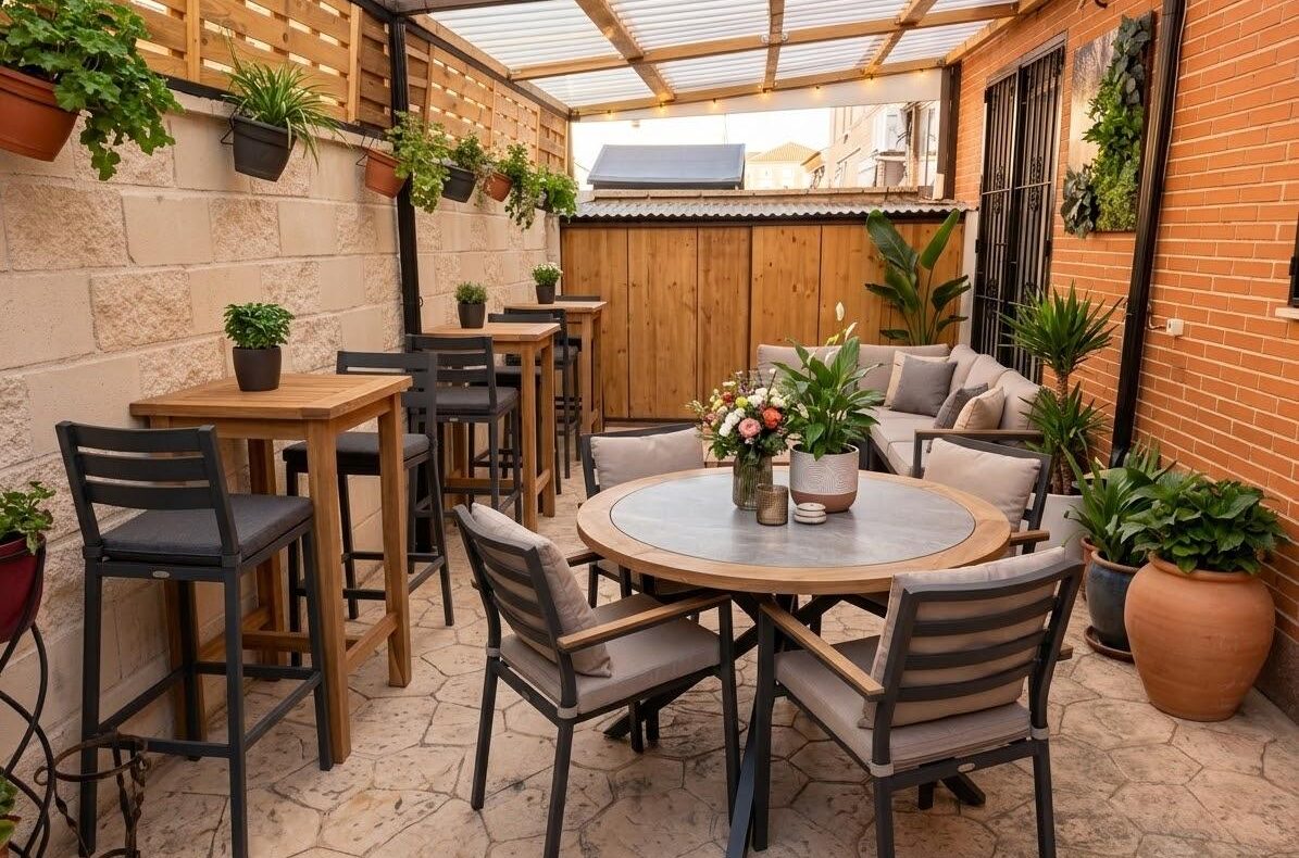 Cozy covered outdoor patio with a round table, cushioned chairs, and potted plants along brick and stone walls.